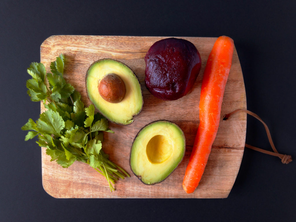 Avocado, Beets, Carrot, and Cilantro on a wooden cutting board. 
