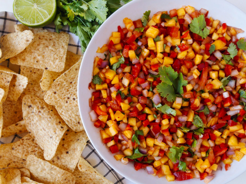 Mango Chili Salsa in a large bowl, surrounded by tortilla chips, limes, and fresh cilantro.