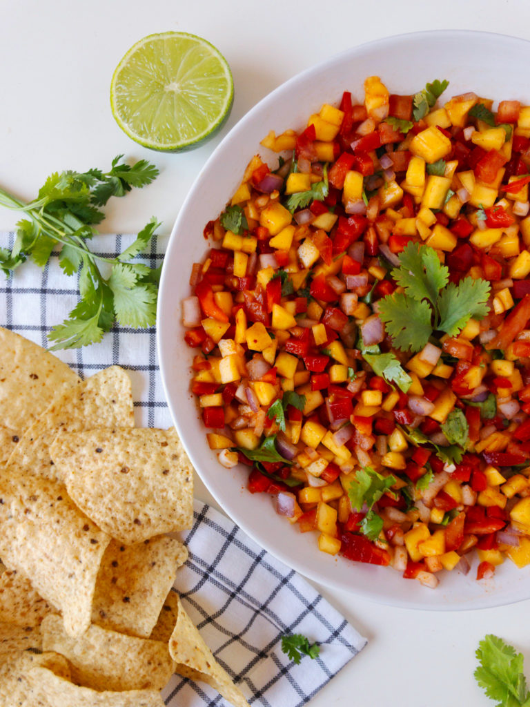 Mango Chili Salsa in a large bowl, surrounded by tortilla chips, limes, and fresh cilantro.