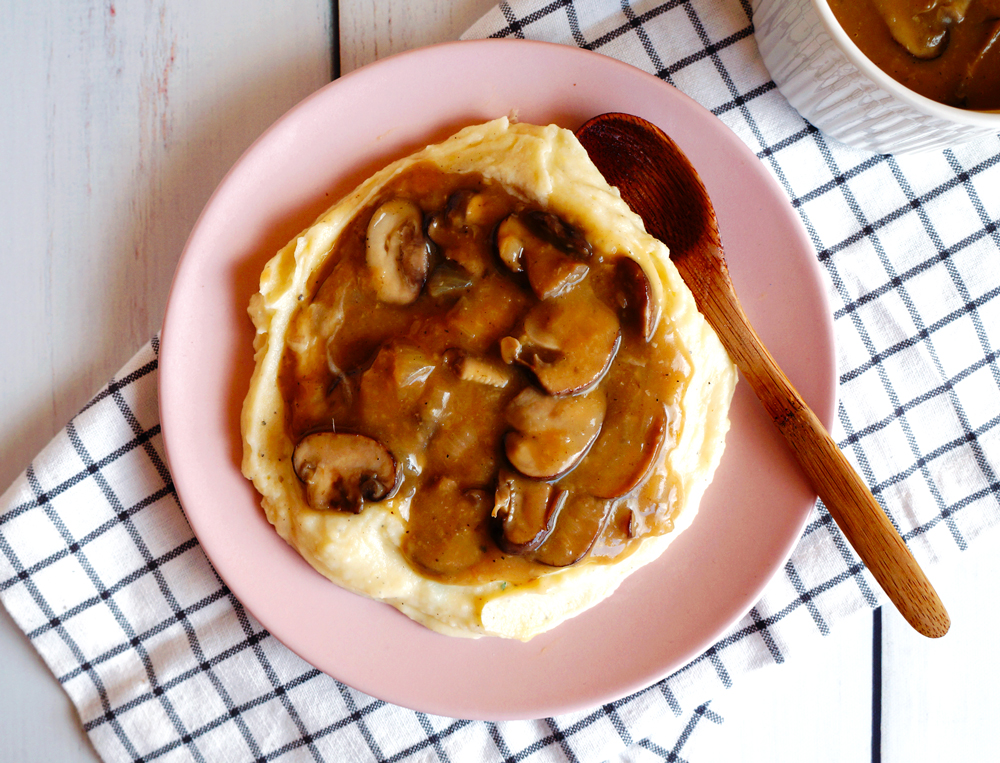 Vegan mushroom gravy with creamy mashed potatoes on a small pink plate.
