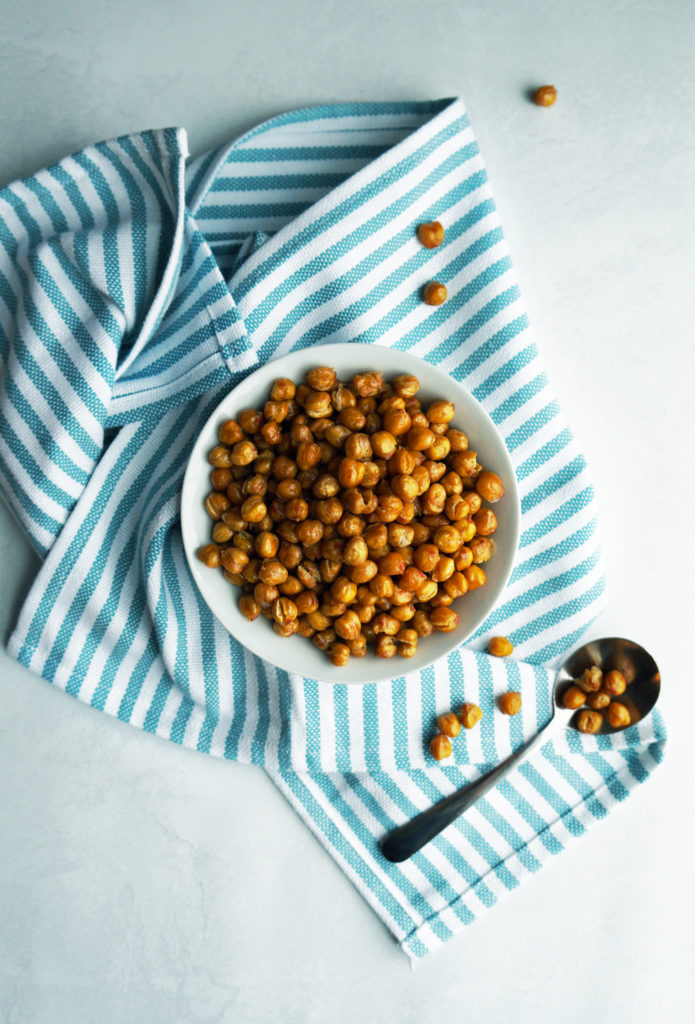 Crispy chickpeas in a small white bowl on a blue and white striped towel.