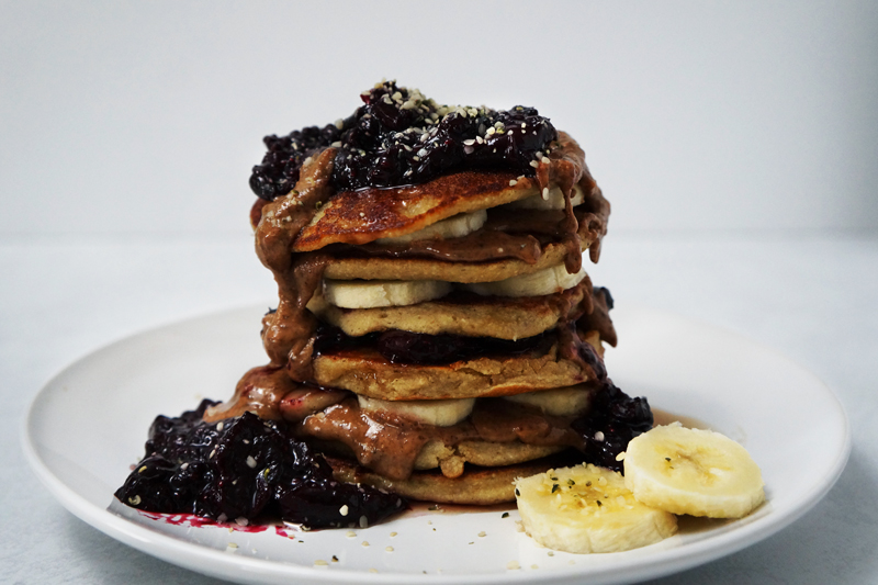 Vegan, gluten-free, single-serving pancakes topped with cherry chia jam, almond butter, maple syrup, and bananas.