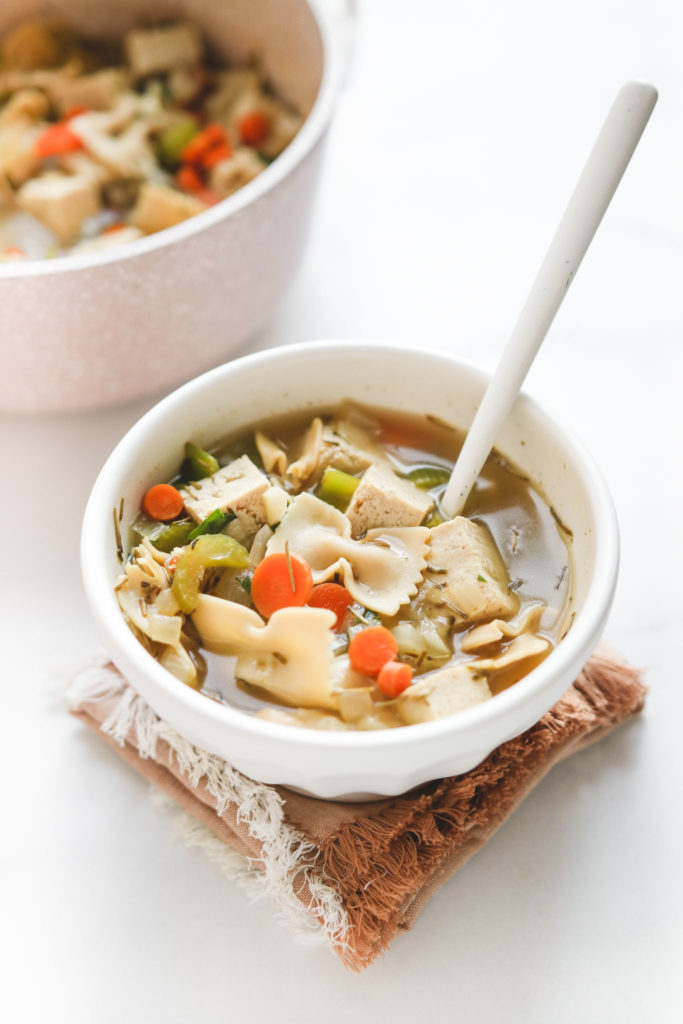 A great vegan pantry recipe – Vegan tofu chicken noodle soup in a small white bowl.