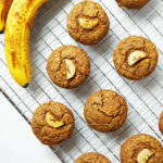 Healthy vegan, gluten-free banana bread muffins on a cooling rack with ripe, spotty bananas.