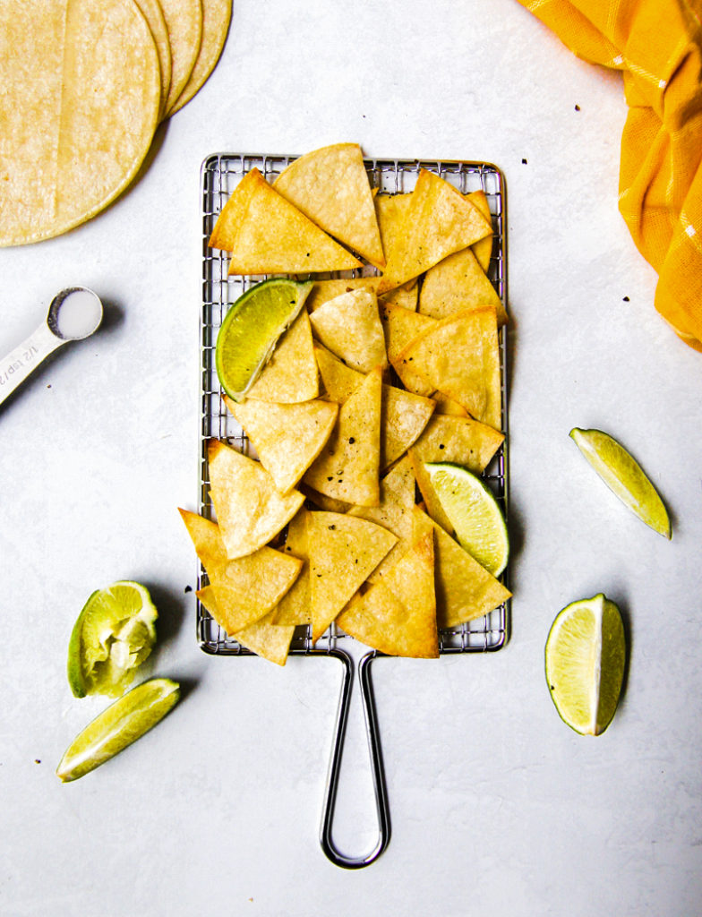 Fresh, crispy, homemade tortilla chips  surrounded by lime wedges and salt.