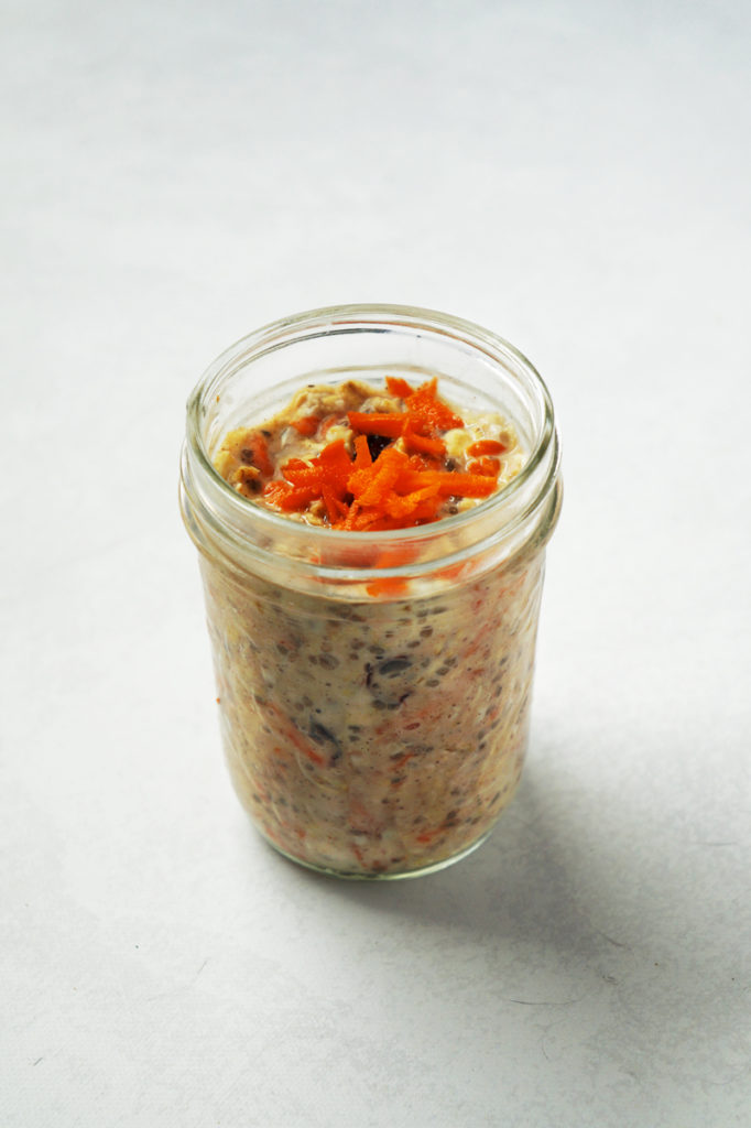Jar of carrot cake oats topped with grated carrots.