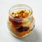 Jar of peanut butter and jelly oats, topped with chopped peanuts.