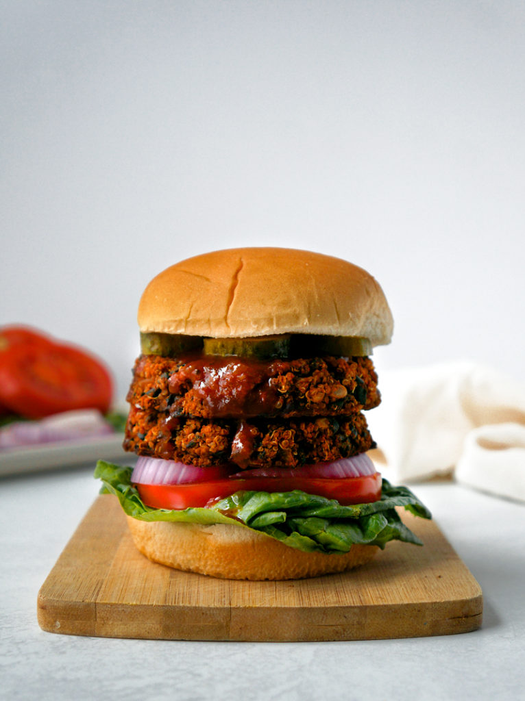 BBQ black bean veggie burger on top of a small wooden cutting board.