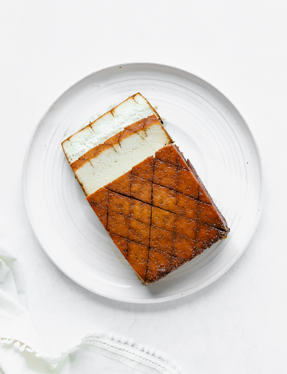 Sliced vegan orange glazed baked tofu on a white plate.